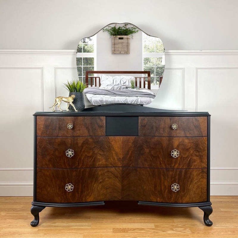 vintage serpentine front dresser with original mirror attached. The body has been hand painted in a rich black mineral paint and the drawer fronts sanded back and stained with an Ebony furniture oil. The original ornate pulls have been polished to a high shine.